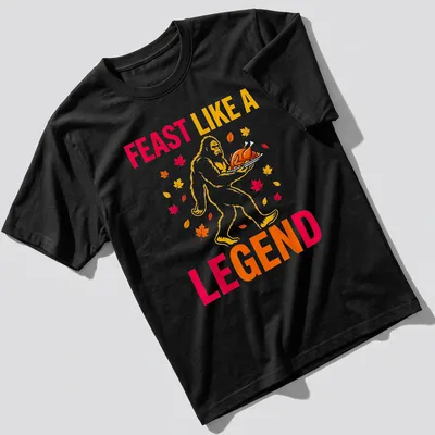 Bigfoot carrying a turkey with the text 'Feast Like A Legend' in colorful cartoon style. — printed on a unisex t-shirt
