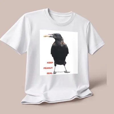 A photographic crow design with the text 'KEEP PEANUT REAL' in black and white. — printed on a unisex t-shirt (angled view)
