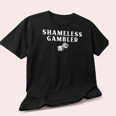 Black and white illustration of dice with the text Shameless Gambler — printed on a unisex t-shirt (angled view)