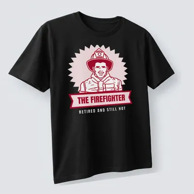 Bold illustration of a firefighter with text 'THE FIREFIGHTER' in red and light pink — printed on a unisex t-shirt (angled view)