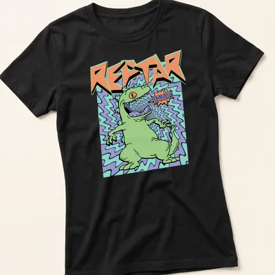 Cartoon green dinosaur roaring with text 'REPTAR RAWR!' in colorful print — printed on a women's shirt