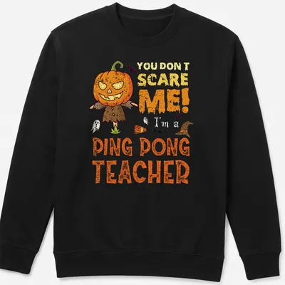 Cartoon pumpkin character with humorous text 'You Don't Scare Me! Ping Dong Teacher' in orange and black — printed on a unisex sweatshirt