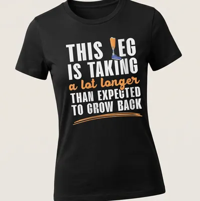 Playful cartoon t-shirt featuring a prosthetic leg humorously remarking on recovery time — printed on a women's shirt