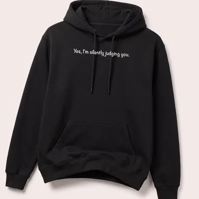 White t-shirt with a playful print stating 'Yes, I'm silently judging you.' — printed on a unisex hoodie