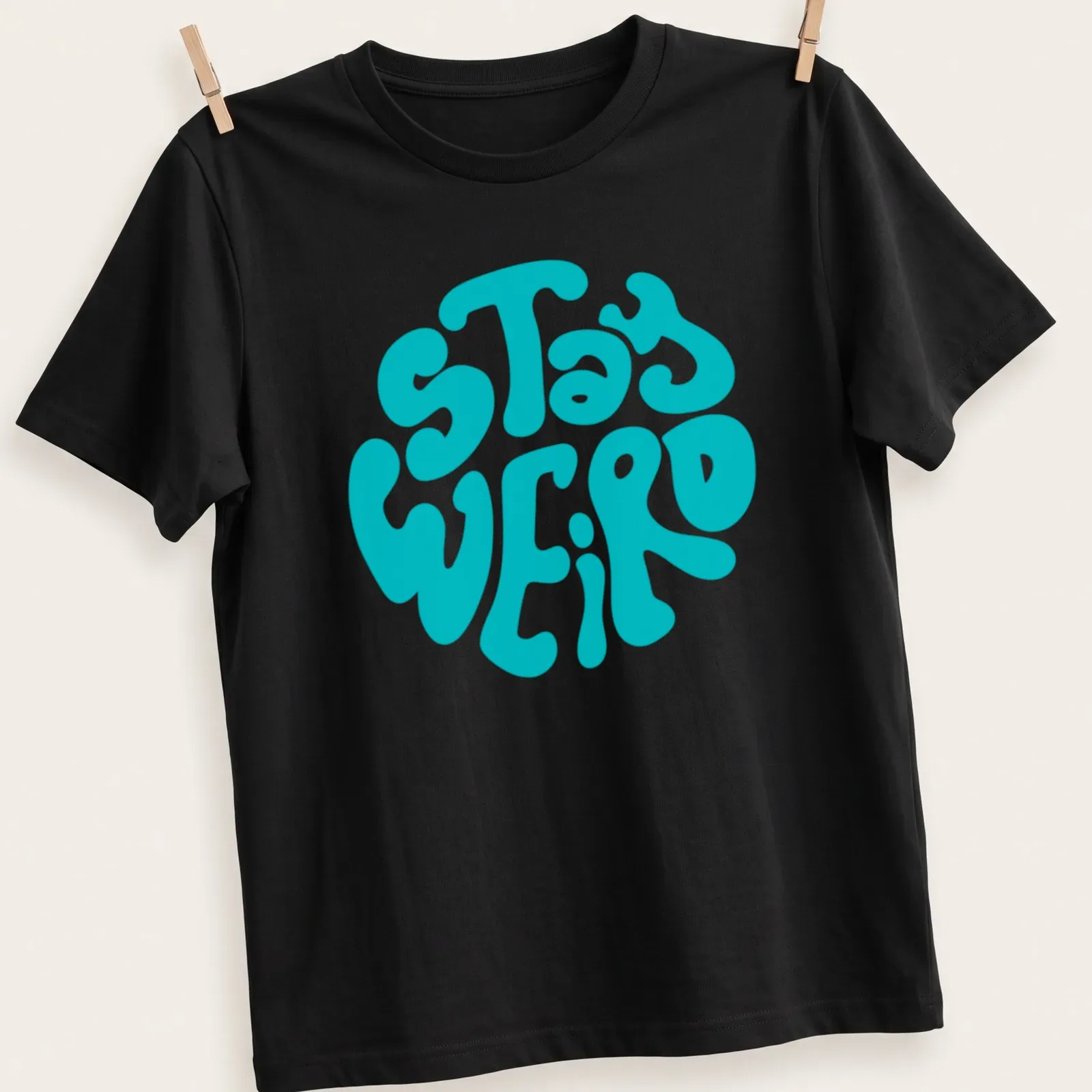 Round design t-shirt with bold 'Stay Weird' text in playful typography — printed on a unisex t-shirt