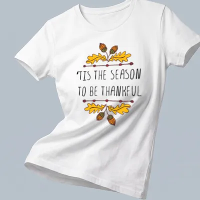 Hand-drawn illustration of autumn leaves and acorns with text 'TIS THE SEASON TO BE THANKFUL' — printed on a women's shirt